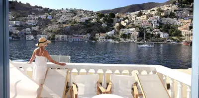 a woman in a hat standing on the deck of a boat at Limani Life in Symi