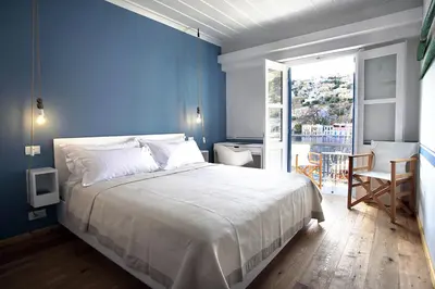 a bedroom with a large bed with a blue wall at Limani Life in Symi