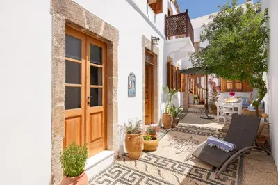 a courtyard of a house with a wooden door and potted plants at Villa Lindia in Líndos