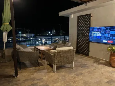 a patio with chairs and a table and a television at Reginas Apartments in Ixia