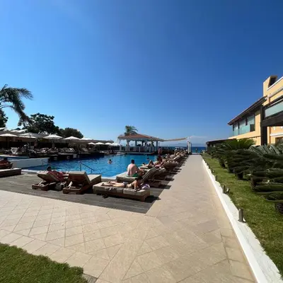 a group of people sitting on lounge chairs by a pool at Reginas Apartments in Ixia