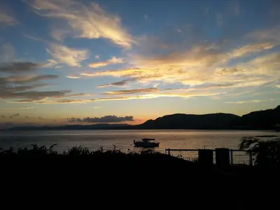 a boat sitting in the water at sunset at Pefkos Beachfront Villa in Pefki Rhodes