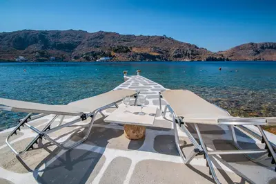 a pair of chairs sitting on a boat in the water at On The Rocks in Symi