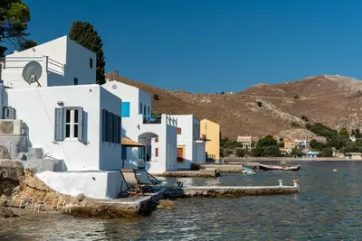 a building on the water next to a body of water at On The Rocks in Symi