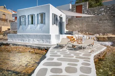 a patio with chairs and a table in front of a building at On The Rocks in Symi