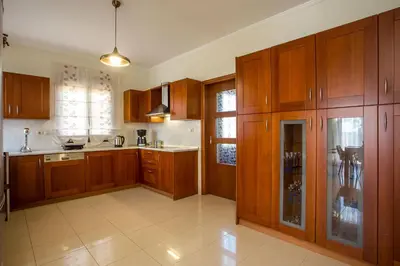 a large kitchen with wooden cabinets at Muses villa in Pastida