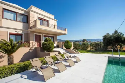 a villa with a swimming pool and chairs at Muses villa in Pastida