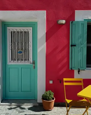 a colorful house with a green door and a table at Casa Di Rosse in Symi