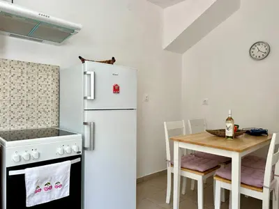 a kitchen with a white refrigerator and a table at Casa Di Rosse in Symi