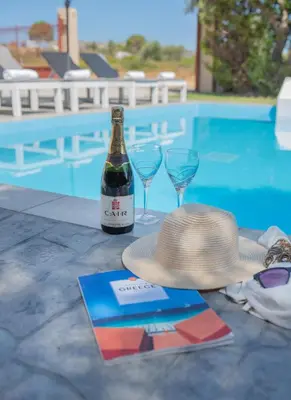 a hat and two wine glasses next to a swimming pool at Emma's Luxury Villa in Pastida