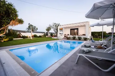 a swimming pool with two chairs and an umbrella at El Sueno Villa in Gennadi