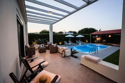 a patio with a pool and chairs and a swimming pool at El Sueno Villa in Gennadi