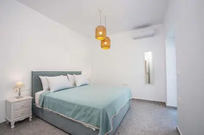 a bedroom with a bed with a blue blanket and a lamp at Kalathos Dream Villas in Kalathos
