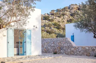 a white house with a blue door and a stone wall at Kalathos Dream Villas in Kalathos