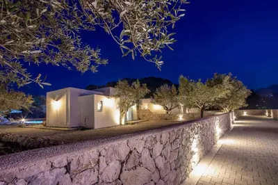 a stone wall in front of a house at night at Kalathos Dream Villas in Kalathos