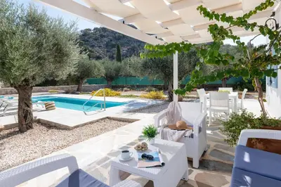 a patio with white furniture and a swimming pool at Kalathos Dream Villas in Kalathos