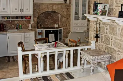 a kitchen with a table and a stone wall at Muse Mese in Halki