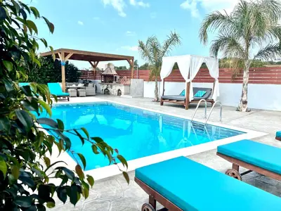 a swimming pool with chairs and a gazebo at Dorieus Villa in Lachania