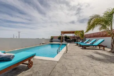 a pool on the roof of a building with blue lounge chairs at Dorieus Villa in Lachania