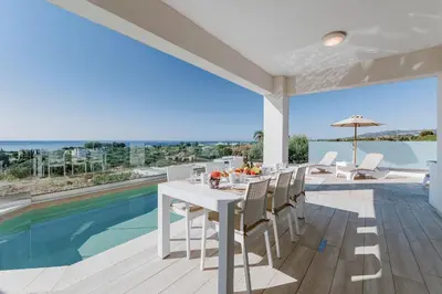 a dining room with a table and chairs and a pool at Villa Oriens in Gennadi