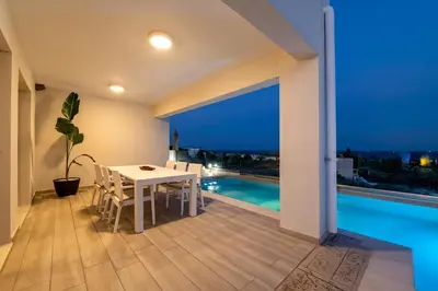 a dining room with a table and a view of a pool at Villa Oriens in Gennadi