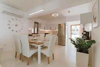 a dining room with a table and chairs and a clock at Villa Oriens in Gennadi