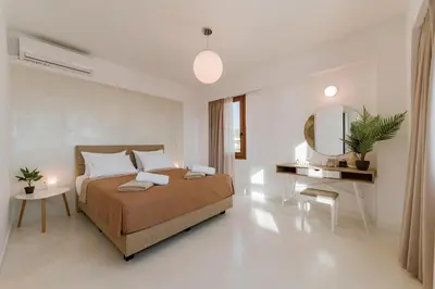 a white bedroom with a bed and a mirror at Villa Eventide in Gennadi
