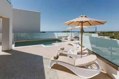 a patio with chairs and an umbrella and a pool at Villa Eventide in Gennadi