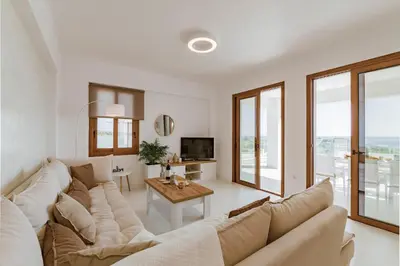 a white living room with a large couch and a table at Villa Eventide in Gennadi