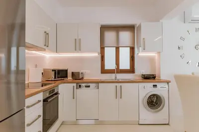 a kitchen with white cabinets and a washer and dryer at Villa Eventide in Gennadi