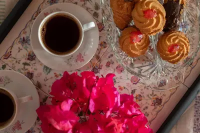 a plate of pastries and a cup of coffee and flowers at Little Karafillias Chalki House in Halki