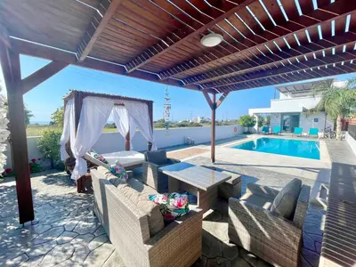 a patio with a couch and a table and a pool at Kallipateira Villa in Lachania
