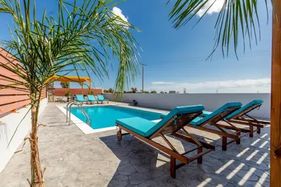 a row of lounge chairs next to a swimming pool at Kallipateira Villa in Lachania