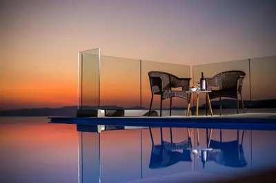 two chairs and a table in front of a body of water at Villa Sophia in Pefki Rhodes