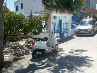 a scooter parked in a parking lot next to a car at Iris Studios in Archangelos