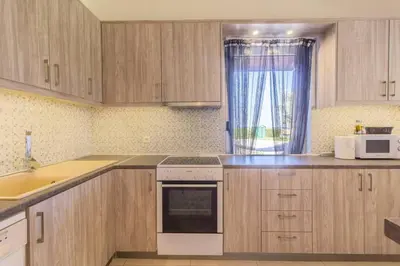 a kitchen with wooden cabinets and a sink and a microwave at Renes Paradise Seahome - Afandou Beach, Rhodes in Rhodes Town