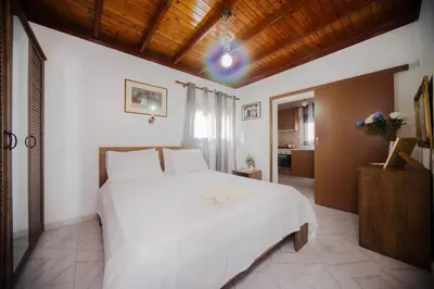 a bedroom with a large white bed and a kitchen at Endless Blue Stegna in Archangelos