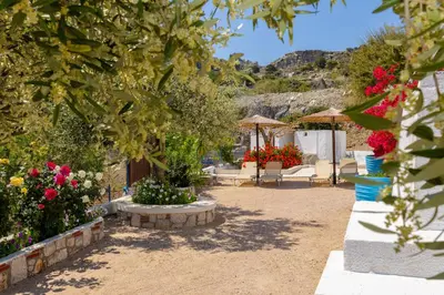 a garden with flowers and tables and umbrellas at Endless Blue Stegna in Archangelos