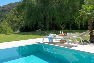 a table and chairs sitting next to a swimming pool at Ixian Hilltop Villa in Triánta