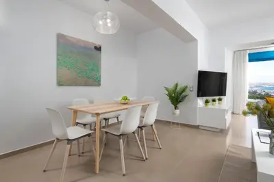 a dining room with a wooden table and white chairs at Aegean View Estates in Faliraki