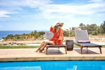 a woman sitting on a chair next to a pool at Anar Villas Rhodes in Koskinou