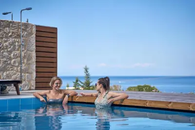 two women sitting in a swimming pool at Anar Villas Rhodes in Koskinou