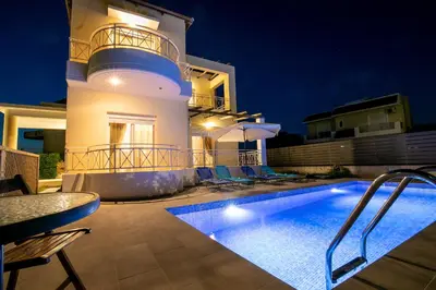 a villa with a swimming pool at night at Rose Garden House in Kremasti