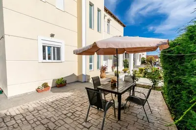 a table and chairs with an umbrella on a patio at Rose Garden House in Kremasti