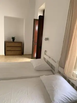a bedroom with two beds and a dresser and a window at PALS Studios Lindos in Líndos