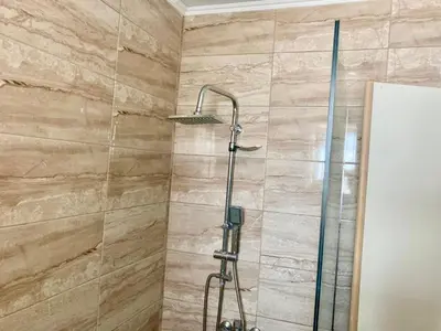 a shower in a bathroom with a stone wall at PALS Studios Lindos in Líndos