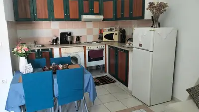 a kitchen with a table with blue chairs and a refrigerator at Old House in Paradeísion