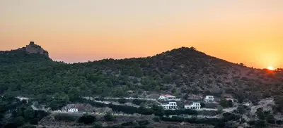 a mountain with a castle on top of it at sunset at Auberge Kalopetri in Kamiros