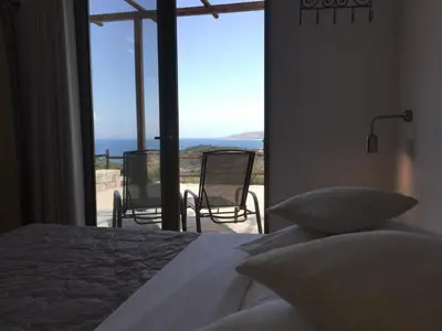 a bedroom with a bed and a view of the ocean at Auberge Kalopetri in Kamiros