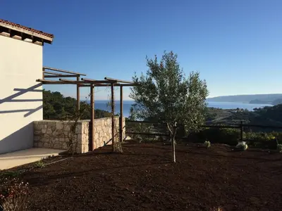 a pergola on the side of a house with a tree at Auberge Kalopetri in Kamiros